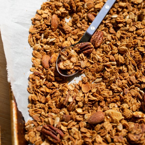 Granola spread out on a sheet of parchment with spoon.