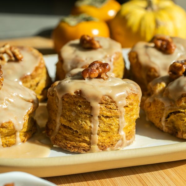 A pumpkin scone with a maple glaze on a white plate.