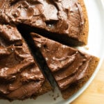 An overhead view of a chocolate-frosted cake with a slice pulled out.