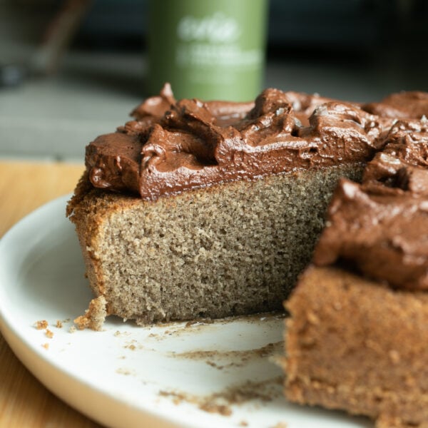 A chocolate-frosted cake on a plate with a slice removed to show the tender crumb.