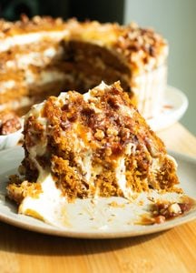 A slice of pumpkin cake on a plate with a bite taken out to reveal the close crumb.