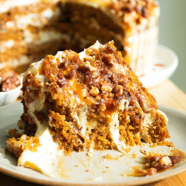 A slice of pumpkin cake on a plate with a bite taken out to reveal the close crumb.