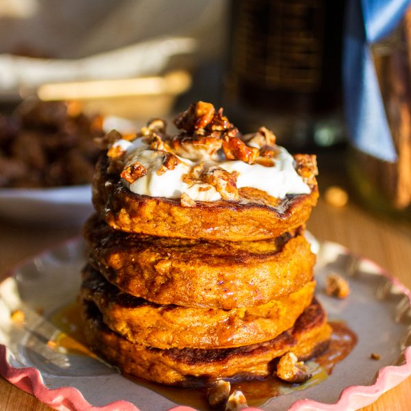 A stack of pumpkin pancakes topped with yogurt and candied walnuts.